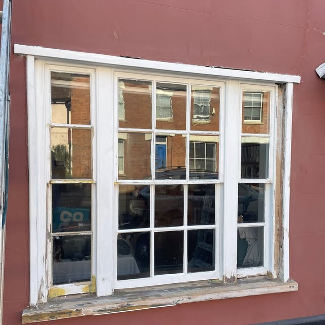 Before: weathered timber sash window on a red wall